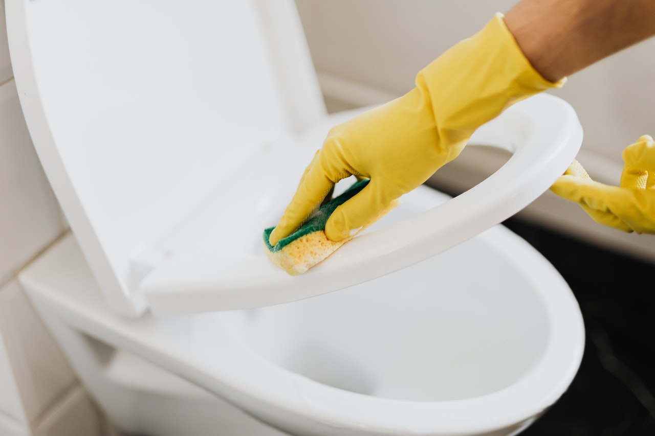 Yellow glove cleaning a toilet seat